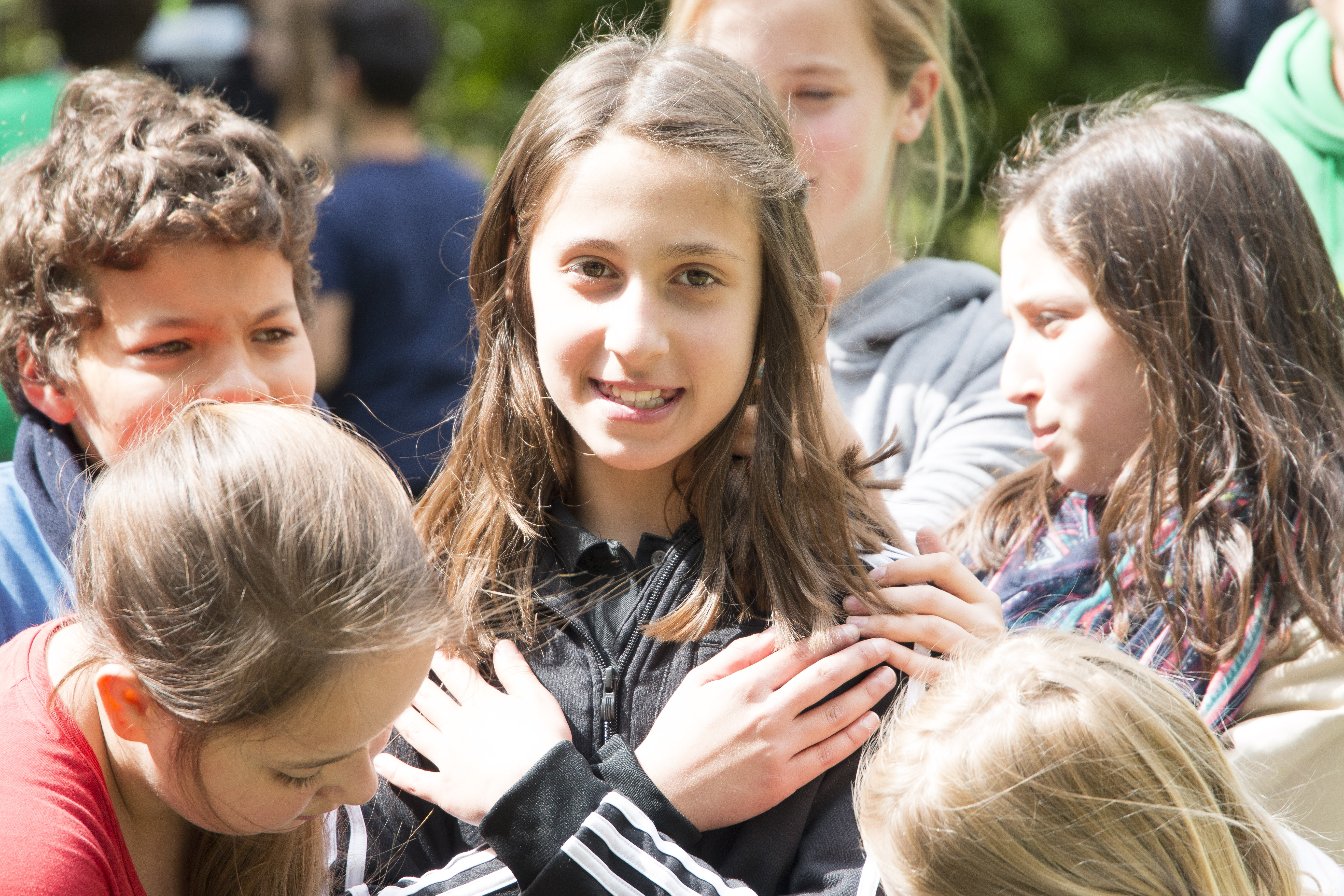 M�dchen mit gekreuzten Armen schaut dich an und steht in Gruppe von Kindern